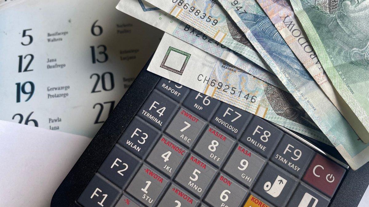 Close-up of Polish Zloty banknotes on a calculator with a calendar in the background.