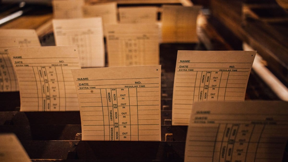 Close-up of vintage time cards in a wooden filing system, showcasing retro workplace documentation.