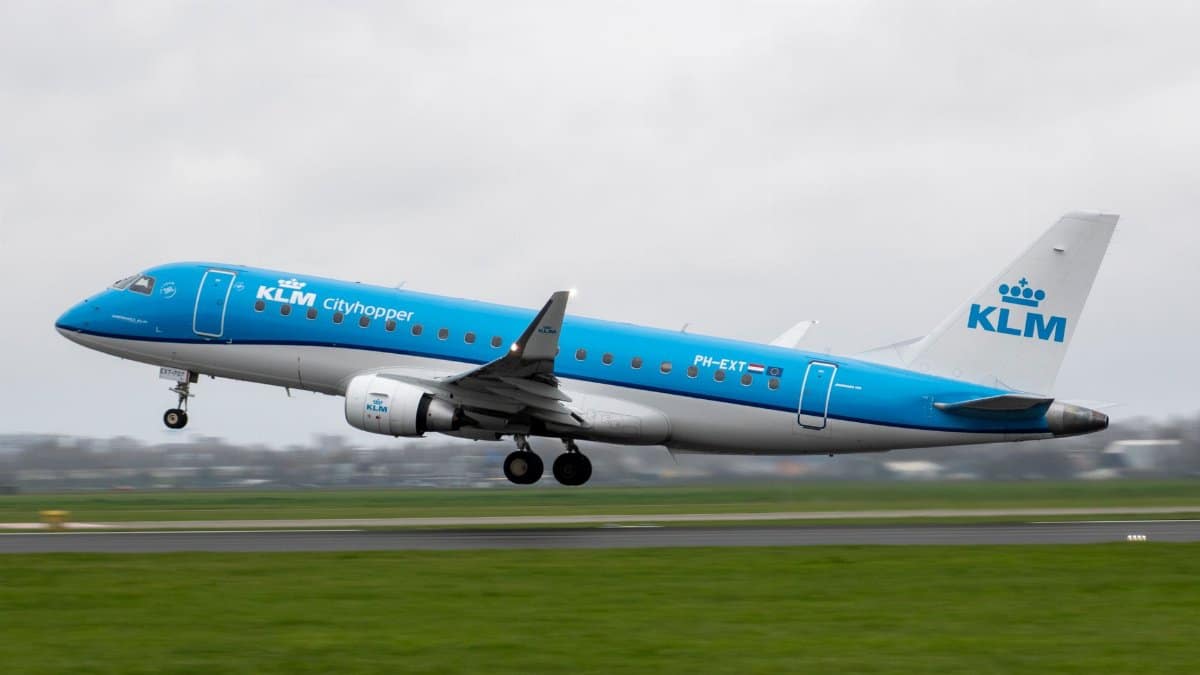 A KLM Cityhopper airplane taking off from a runway at an airport on a cloudy day.