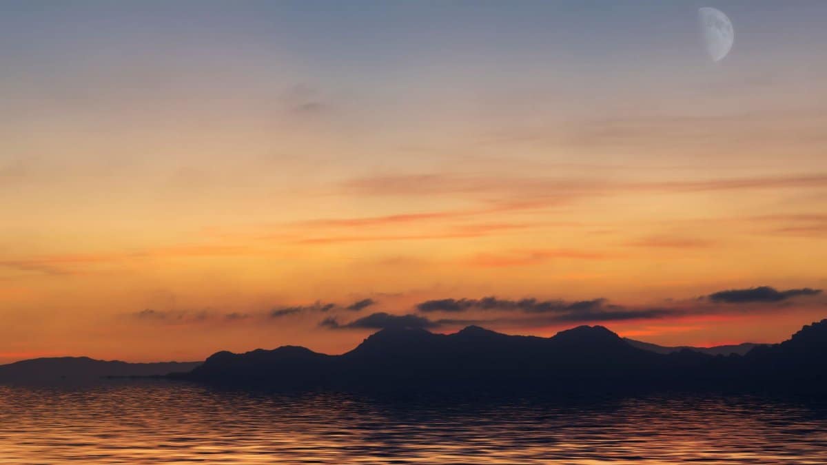 Tranquil ocean view during a vibrant sunset with distant mountains and a crescent moon.