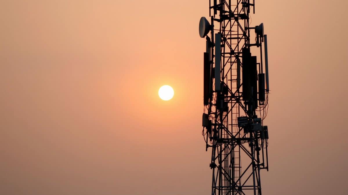 A striking silhouette of a communication tower against a vibrant sunset sky.