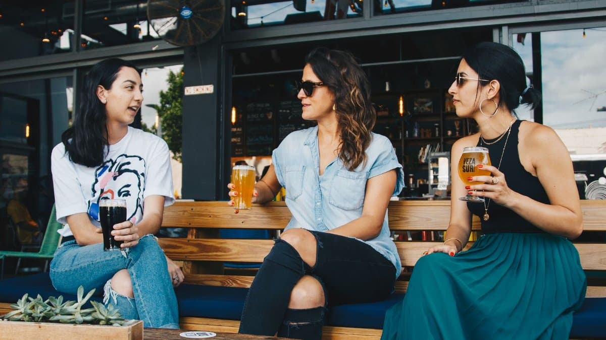A group of women in conversation enjoying drinks at an outdoor bar.