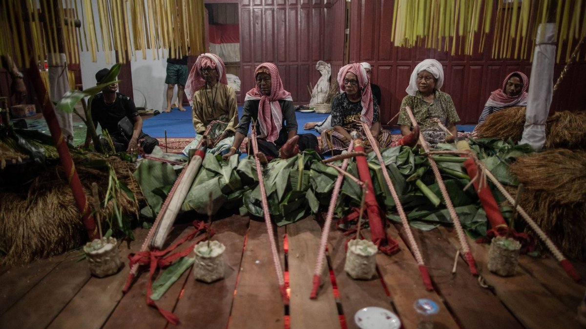 Group participating in a traditional cultural ceremony with ritual elements indoors.