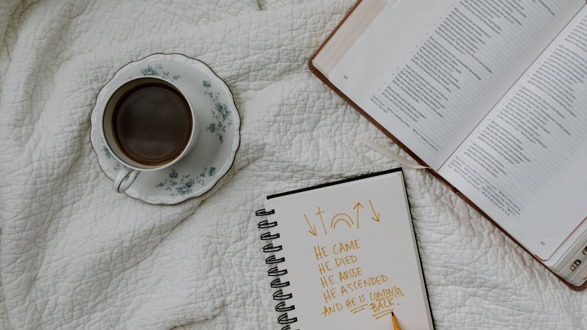 A setting of morning Bible study with coffee, notes, and a quilted fabric backdrop.