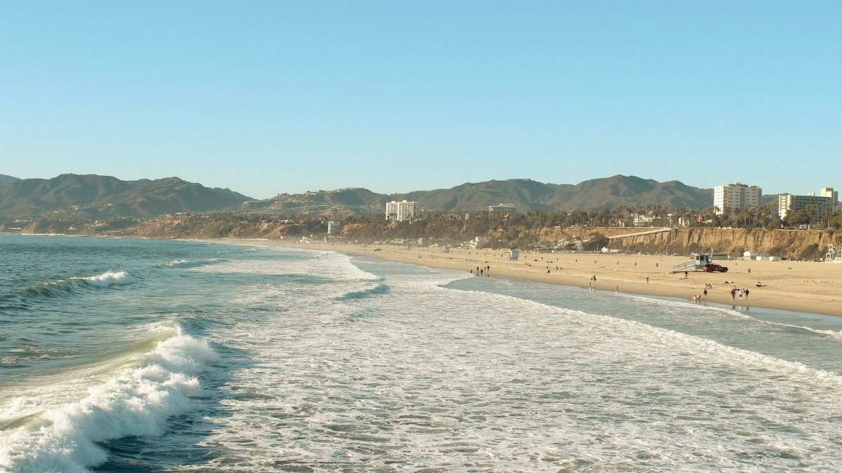A beautiful view of Santa Monica beach and mountains with clear skies.