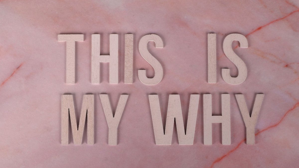 Wooden letters forming a motivational message on a pink marble backdrop, perfect for inspiration.