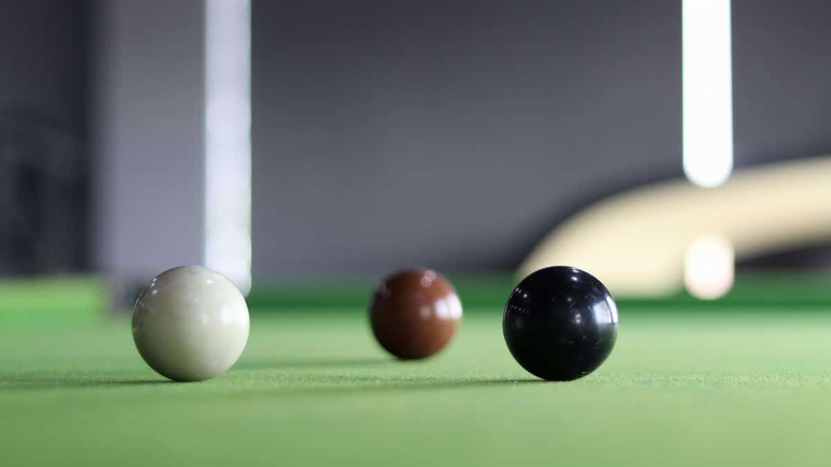 Three colored snooker balls arranged on a green snooker table with blurred background.