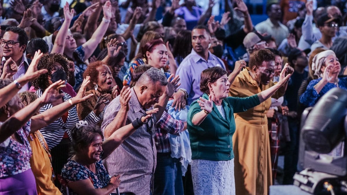A diverse crowd engaged in spiritual prayer at an indoor community event.