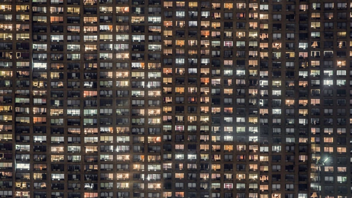 A detailed view of an urban apartment building's lit windows at night.