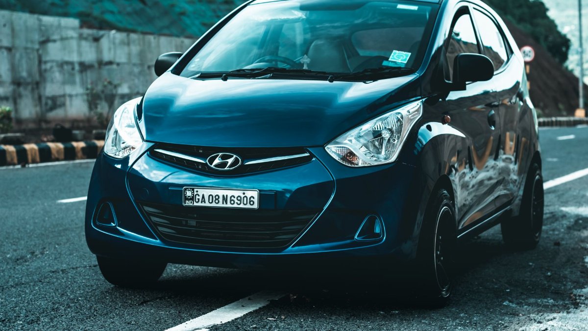 A vibrant blue Hyundai hatchback car parked on a scenic asphalt road, perfect for travel themes.