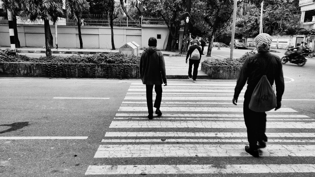 People crossing a city street in a monochrome setting, capturing urban life.