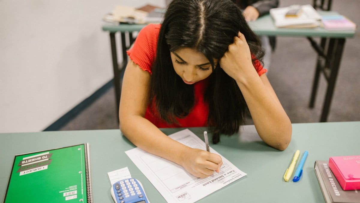 A focused college student studying at her desk during an exam preparation session.