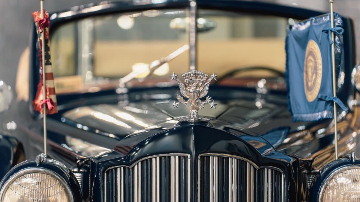 Close-up of a vintage ceremonial car with presidential emblem and flags displayed prominently.
