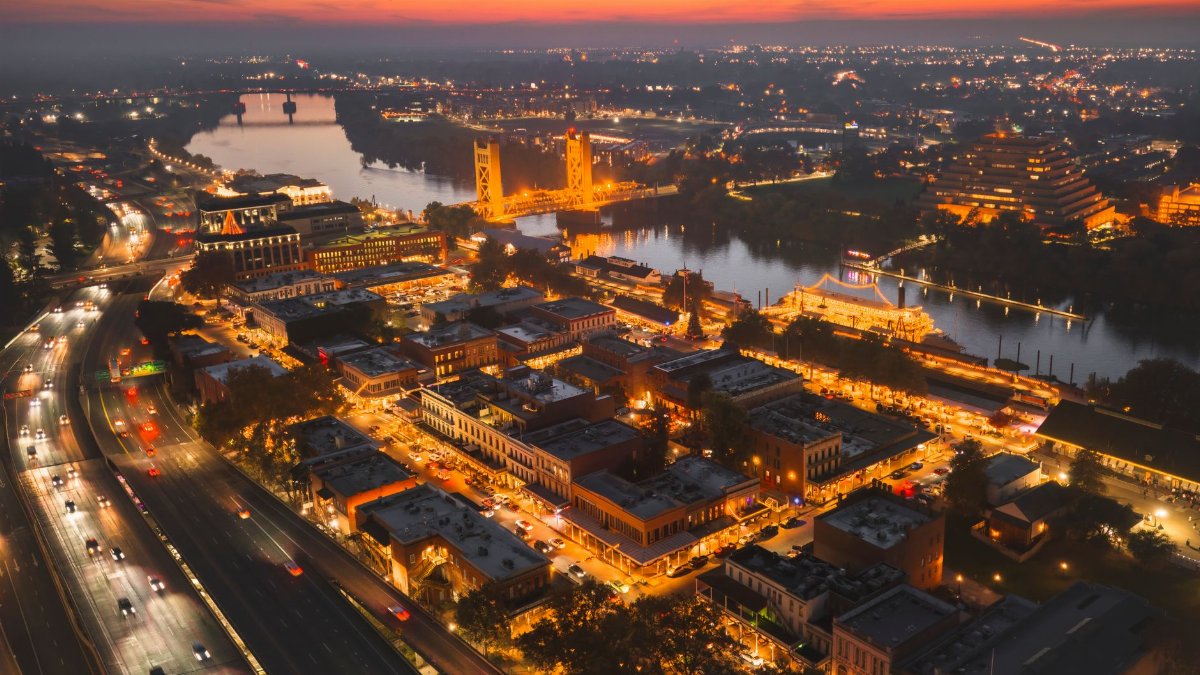 Stunning aerial view of Sacramento Tower Bridge at sunset, highlighting vibrant city lights along the river.