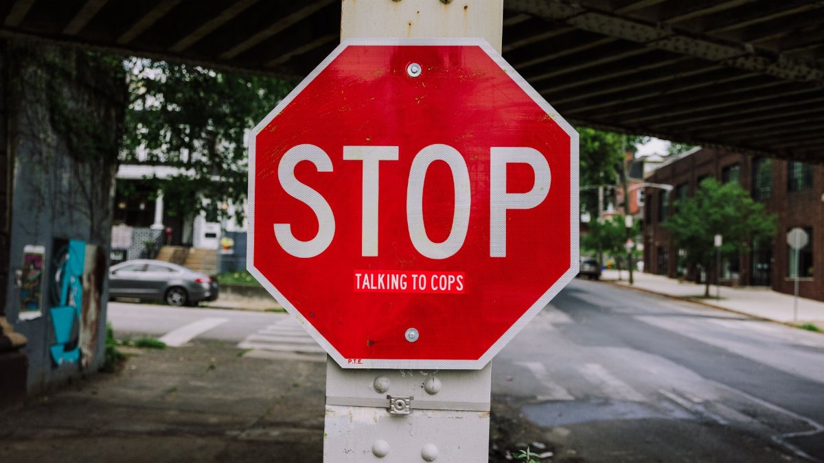 A red stop sign with humorous text 'talking to cops' on an urban city street corner.