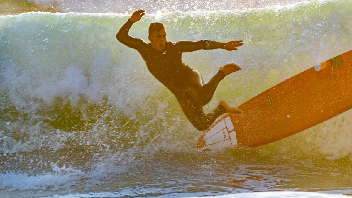 A surfer experiences a wipeout on an ocean wave, capturing the excitement of summer surfing.