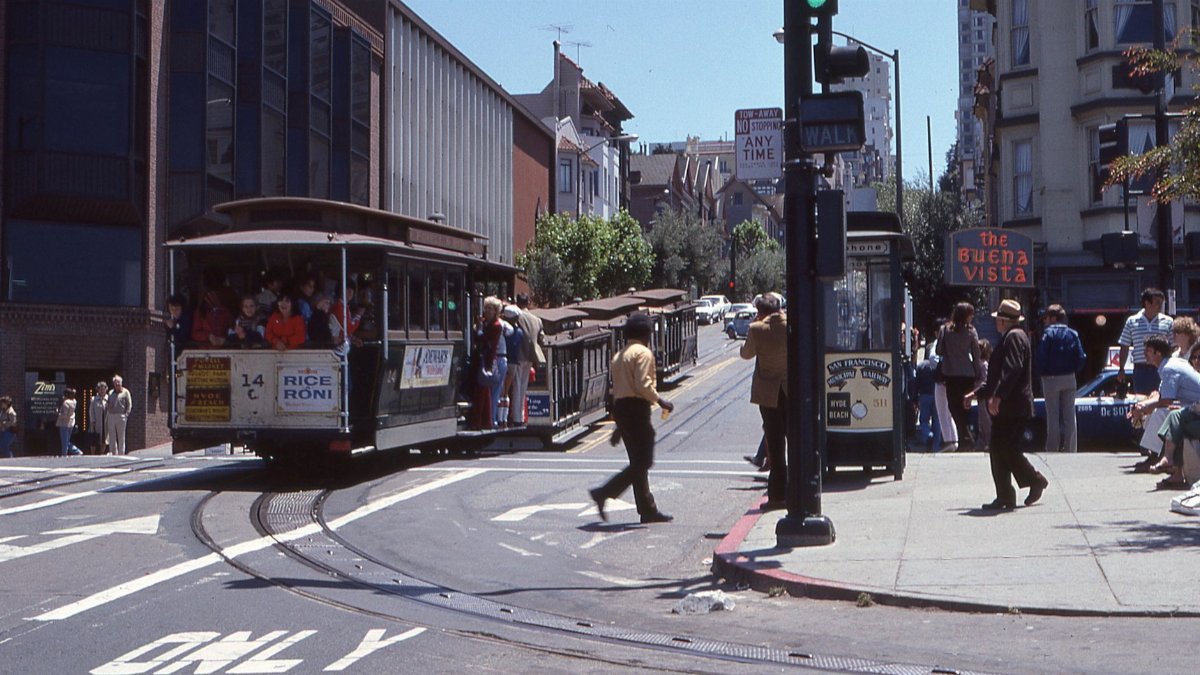 Iconic San Francisco cable car navigating bustling urban street. Captures vibrant city life and transportation.
