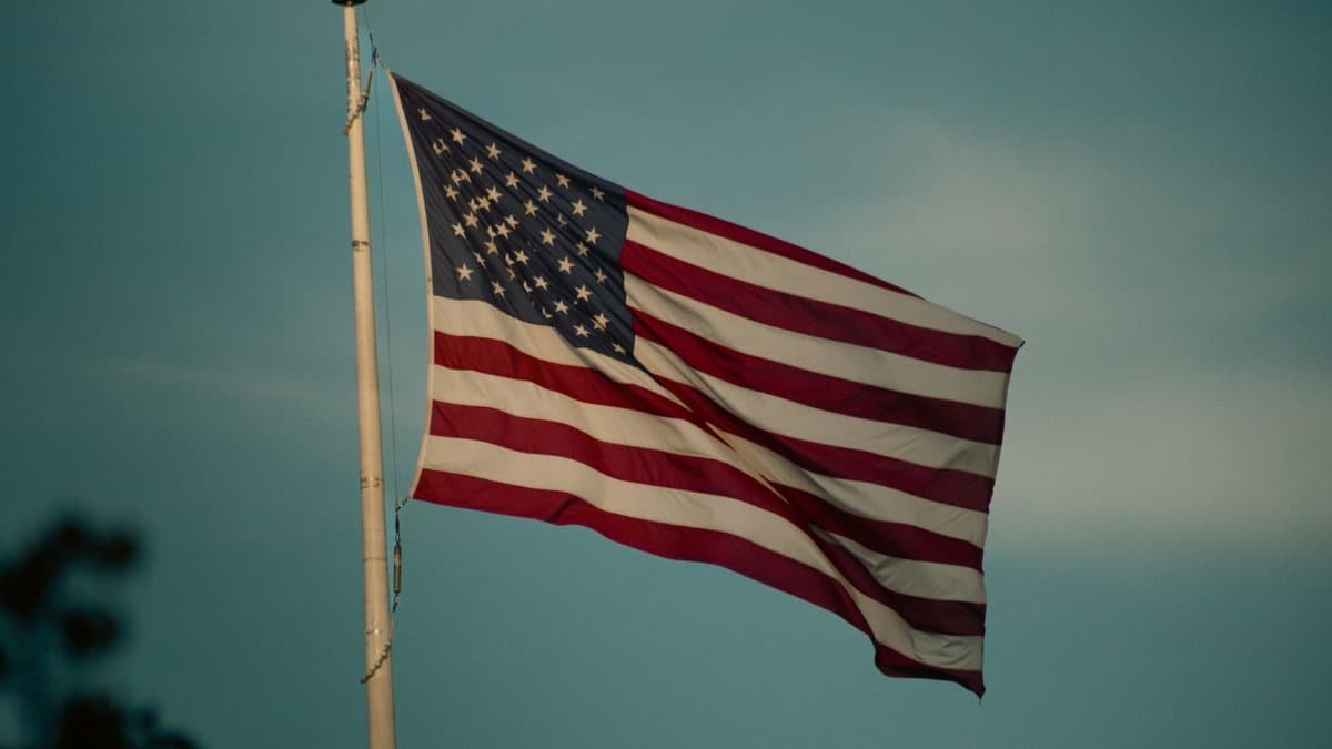 American flag waving on a flagpole against a clear blue sky.