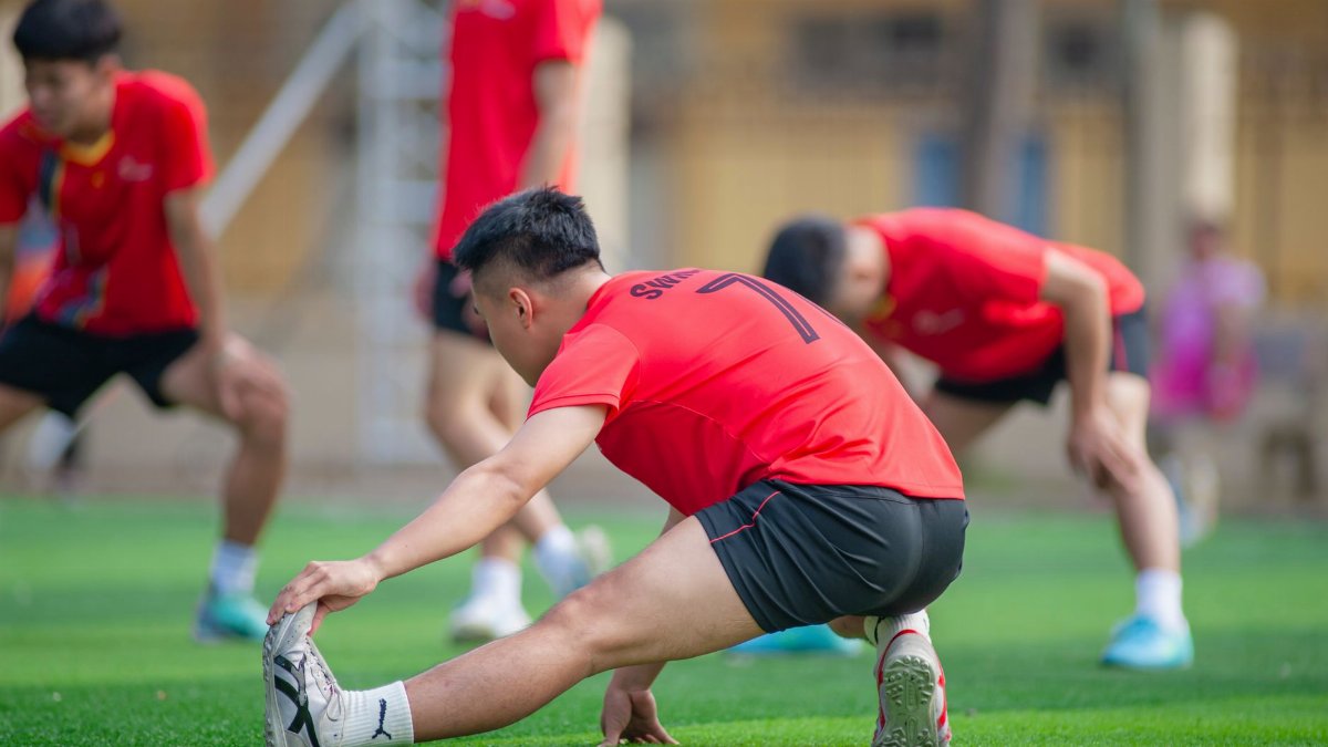 Young athletes stretch before a soccer game in Hanoi, showcasing teamwork and fitness.