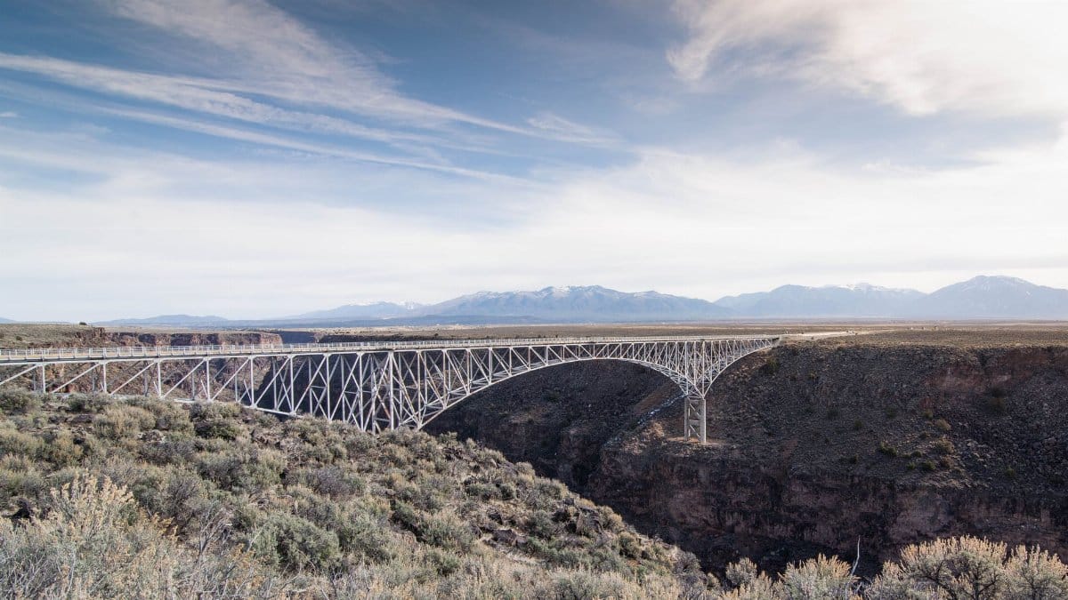 Scenic daylight shot of the Rio Grande Gorge Bridge with mountain backdrop.