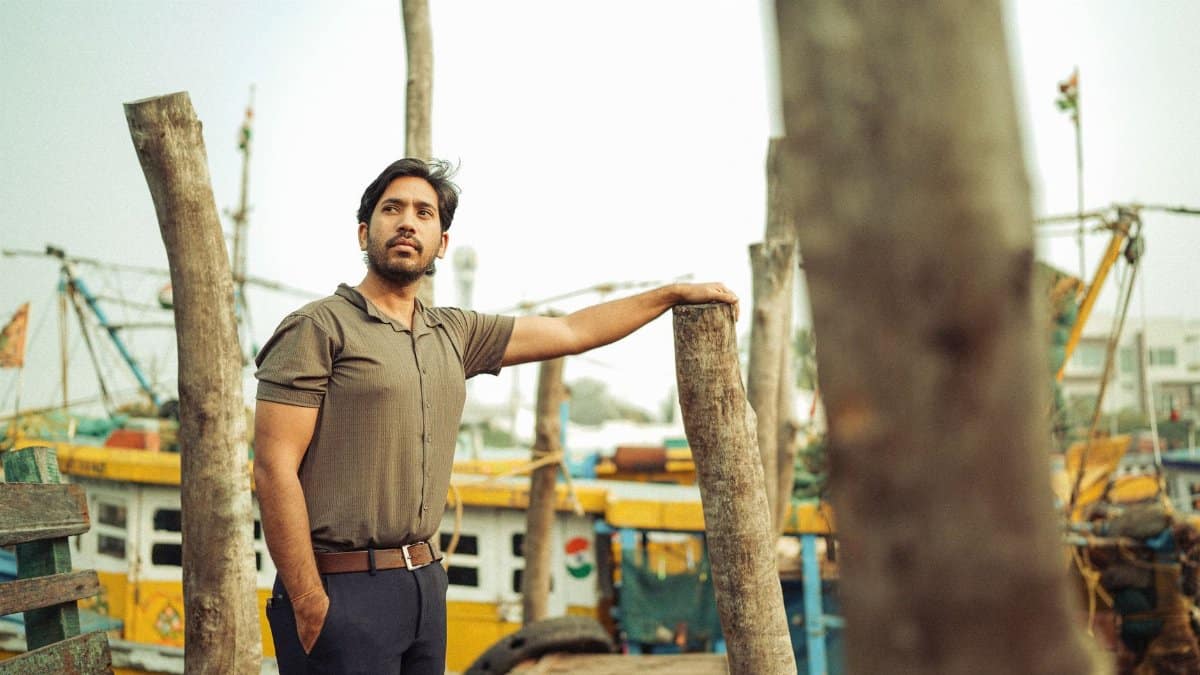 An adult man stands on a fishing boat dock. Scenic outdoor setting.