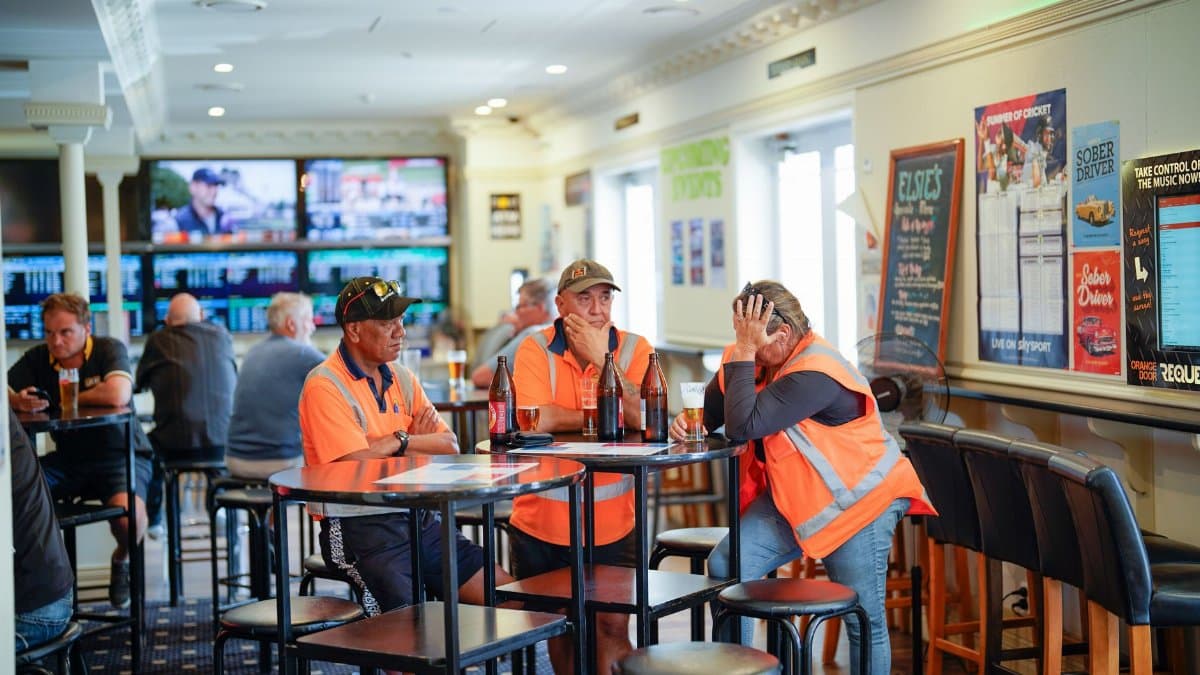 Workers in reflective vests enjoying drinks at a pub in Tuakau, New Zealand.