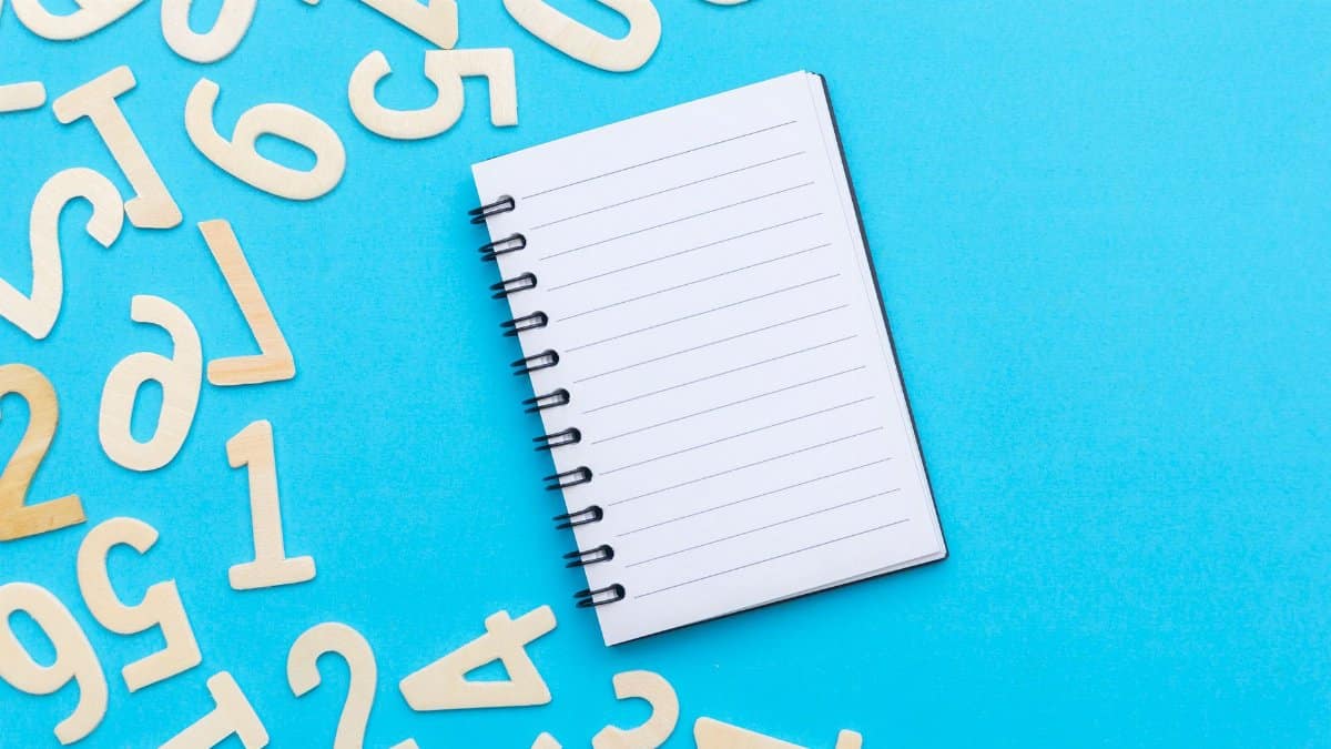 Top view of blank notebook with scattered numbers on a vibrant blue background.