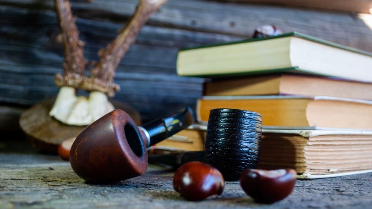 Cozy rustic setting featuring wooden pipes, stacked books, and antler decor on a wooden surface.